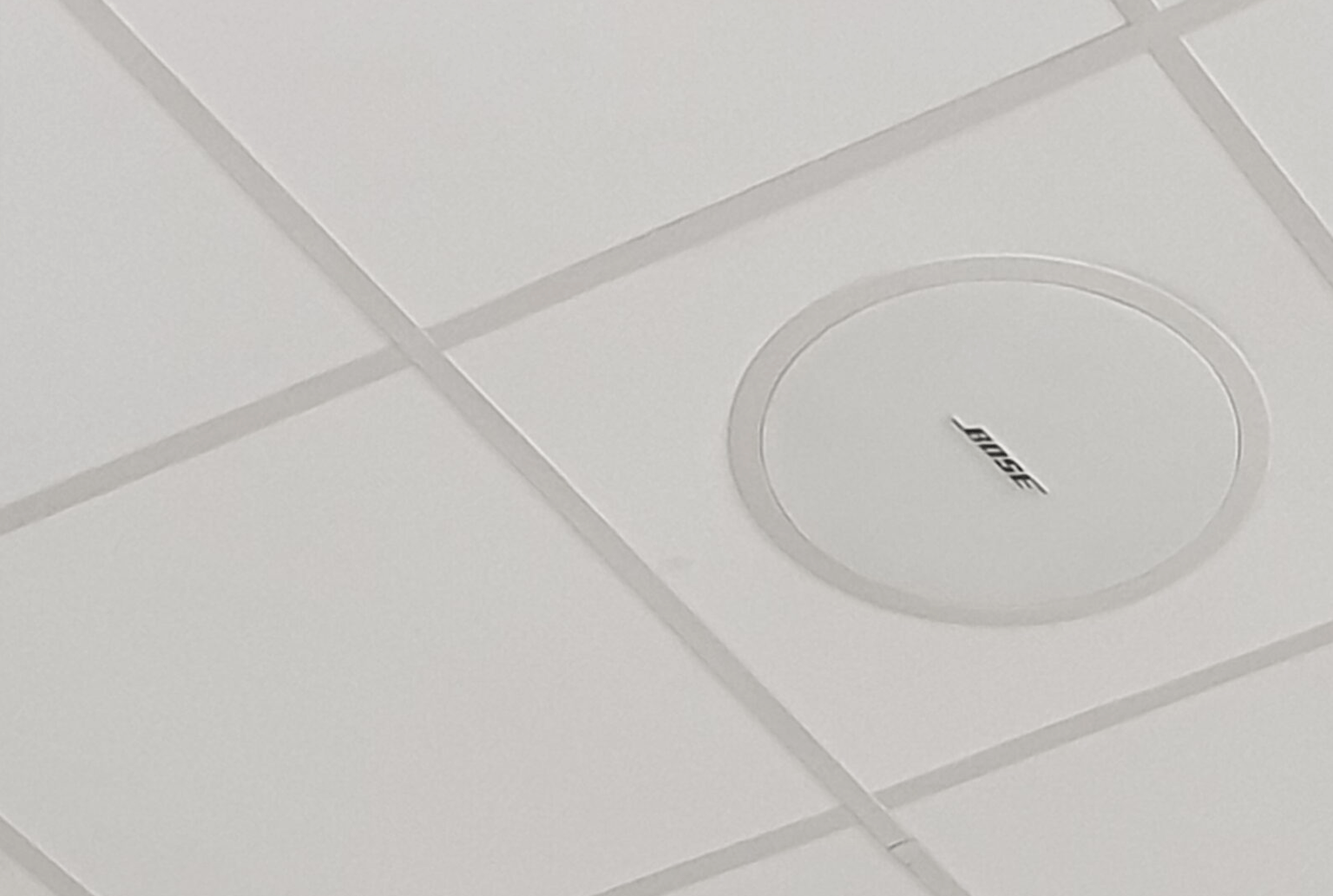 A white bose ceiling speaker installed into a restuarant