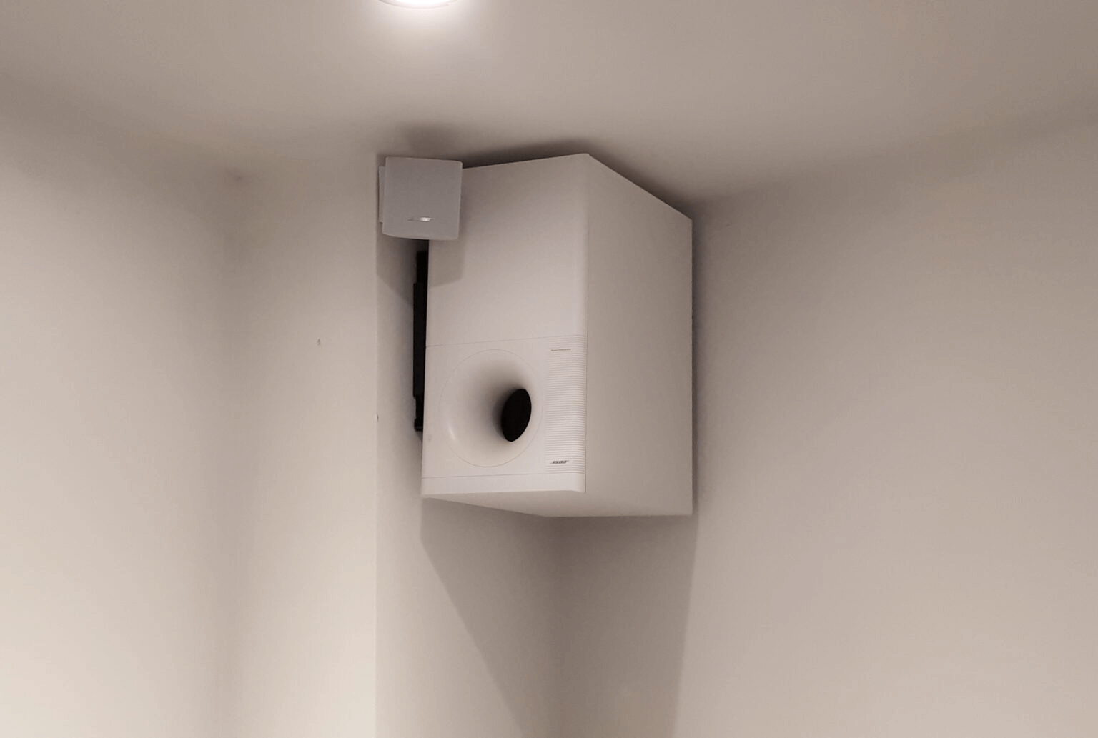 A white bose subwoofer speaker installed in a restaurant